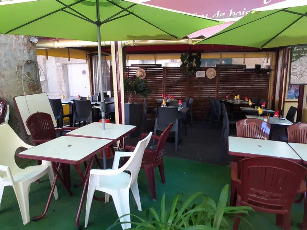 La terrasse extérieure sous les parasols verts, tables et chaises blanches